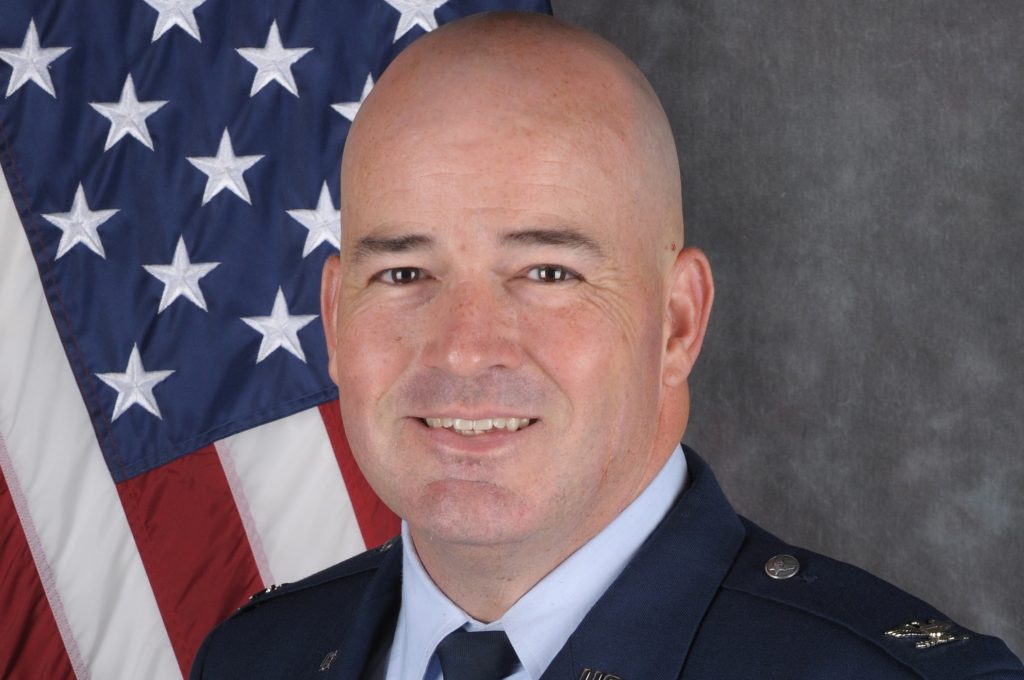 Col Will Marshall, US Air Force, in a formal posed image in dress uniform, in front of an American flag. [US Air Force photo]