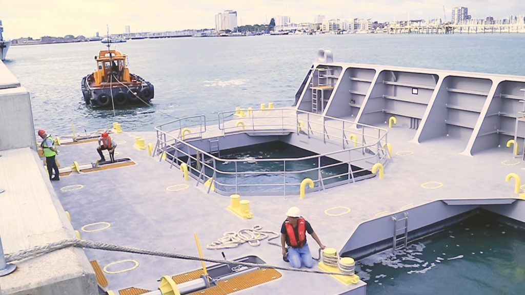 The Fendered Space Units are grey with yellow markings around them. They are pictured on the sea with people working on the units