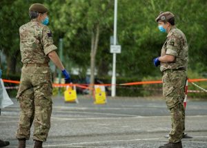 Two Reservists stand apart in Army uniform at a mobile testing facility for Coronavirus in london. 