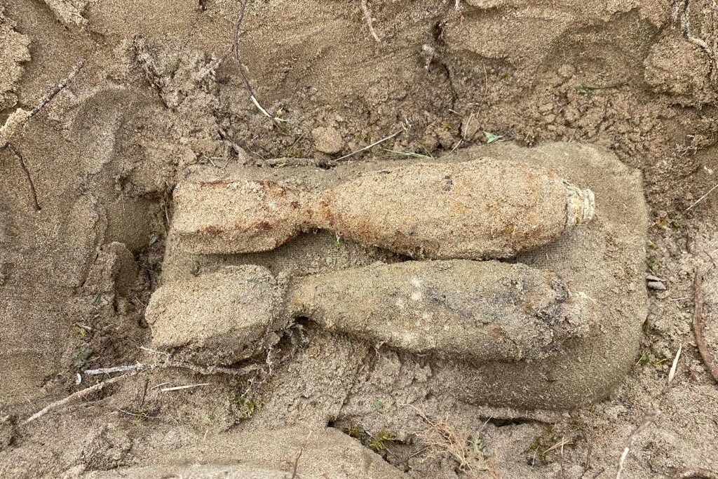 The photo shows two unexploded mortar shells which have been excavated from an area of rocky ground.