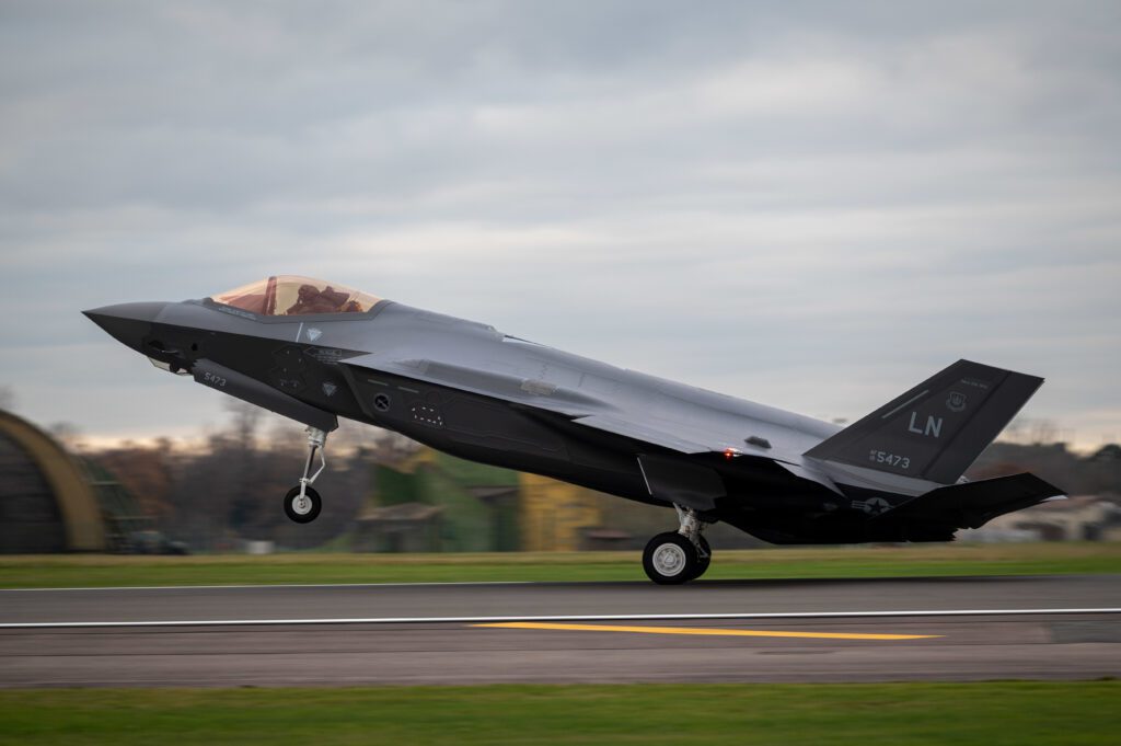 An F-35 lands on a runway, with the rear wheels touching the runway but the front wheels still in the air.
