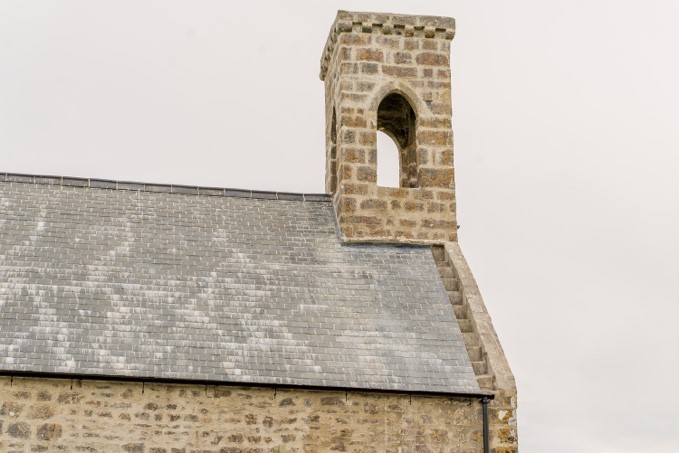 The refurbished roof of the chapel, with cleanly-laid bricks across the roof and spire.