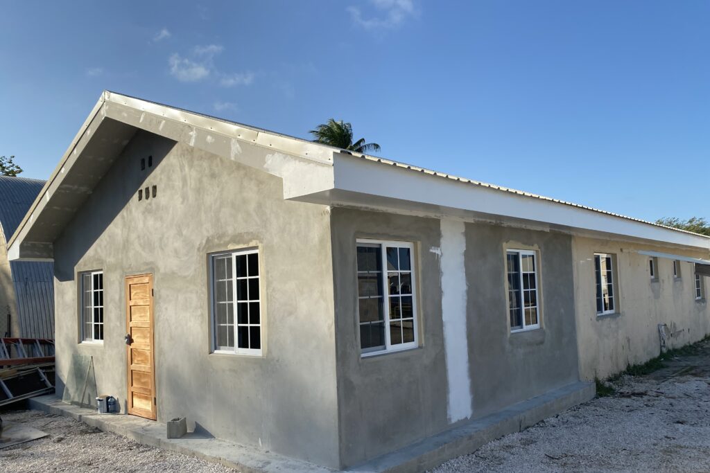 Photo showing a single storey building on which an extension is in progress. Above is a clear, blue sky.