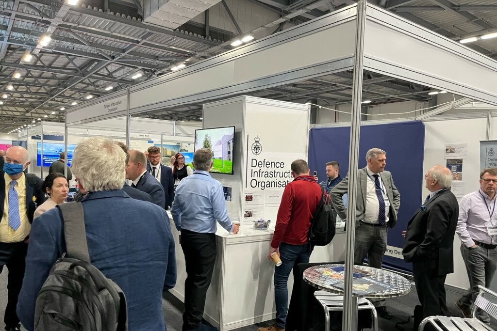 An image taken at the DIO stand during the DPRTE conference. It is a busy scene, with various individuals stood talking and looking at the information on display.