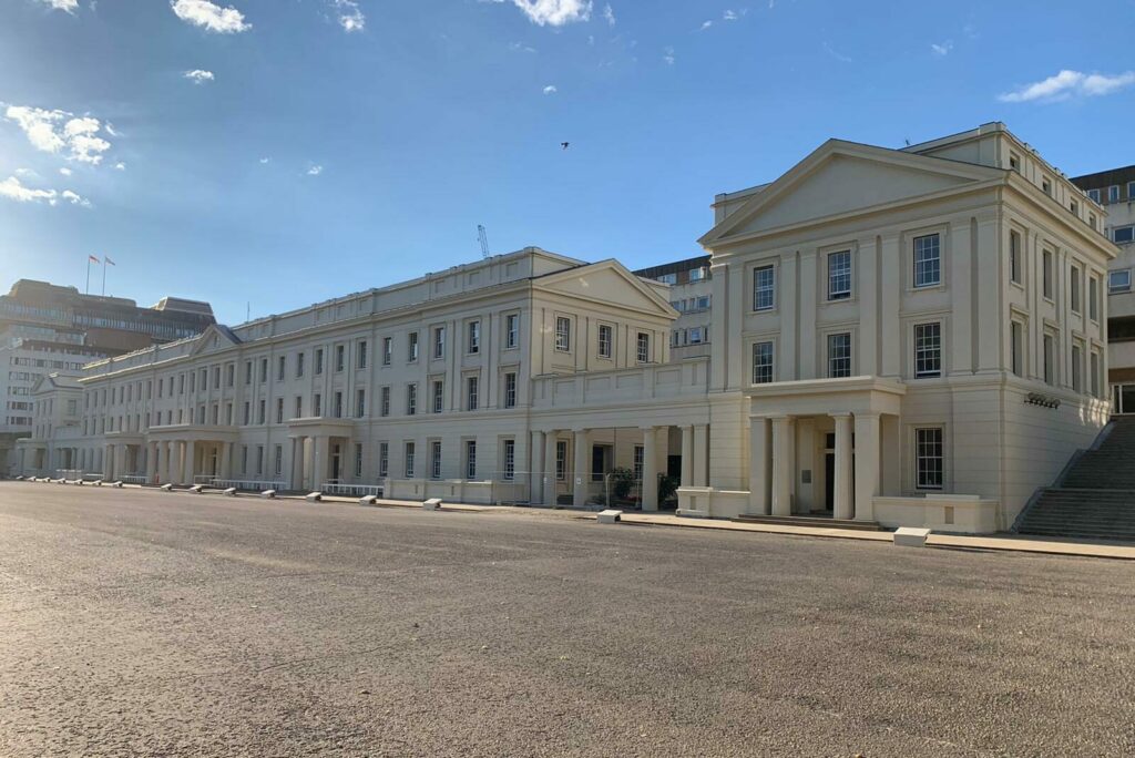 A front-facing view of Wellington Barracks, a military Grecian style building featuring an external facade and columns in front of its main entrances.