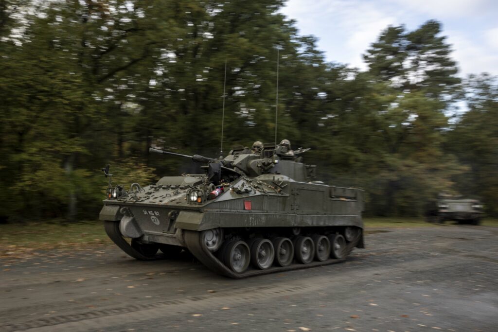 a military vehicle with two soldiers in the turret driving past at speed