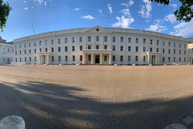 A front-facing view of Wellington Barracks, a military Grecian style building featuring an external facade and columns in front of three doorways.