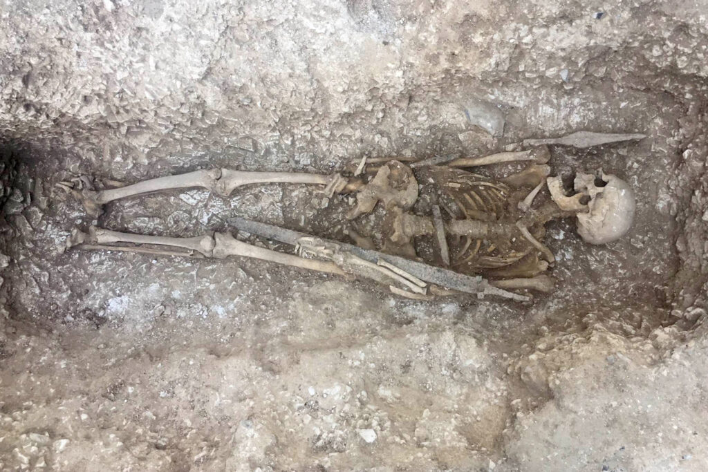 A skeleton lying in a section of excavated grave