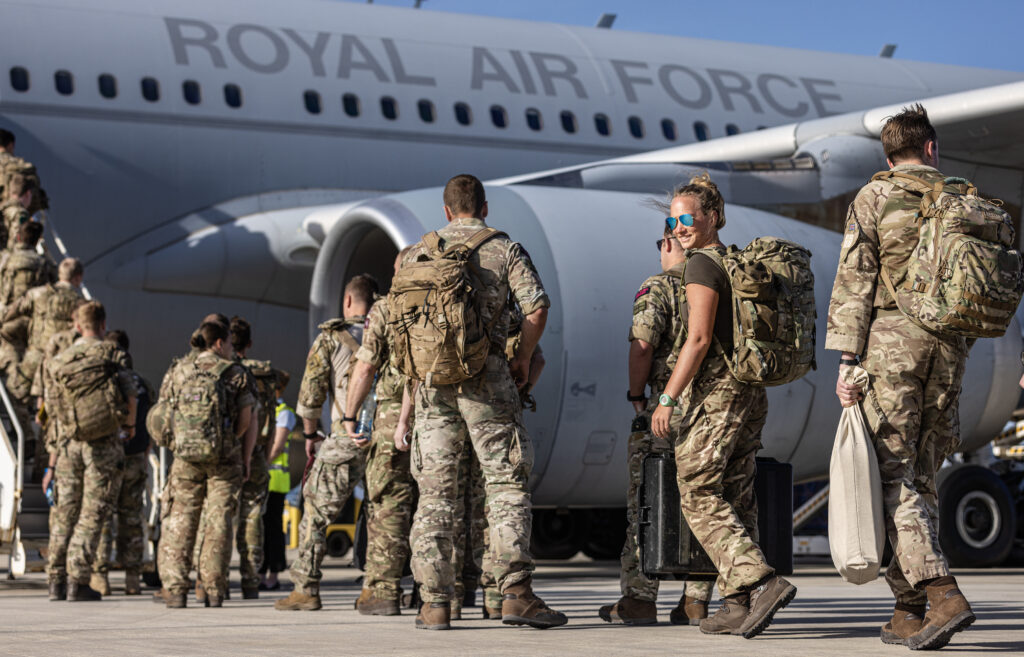 A group of approximately ten service personnel line up outside a large grey RAF transport aircraft.