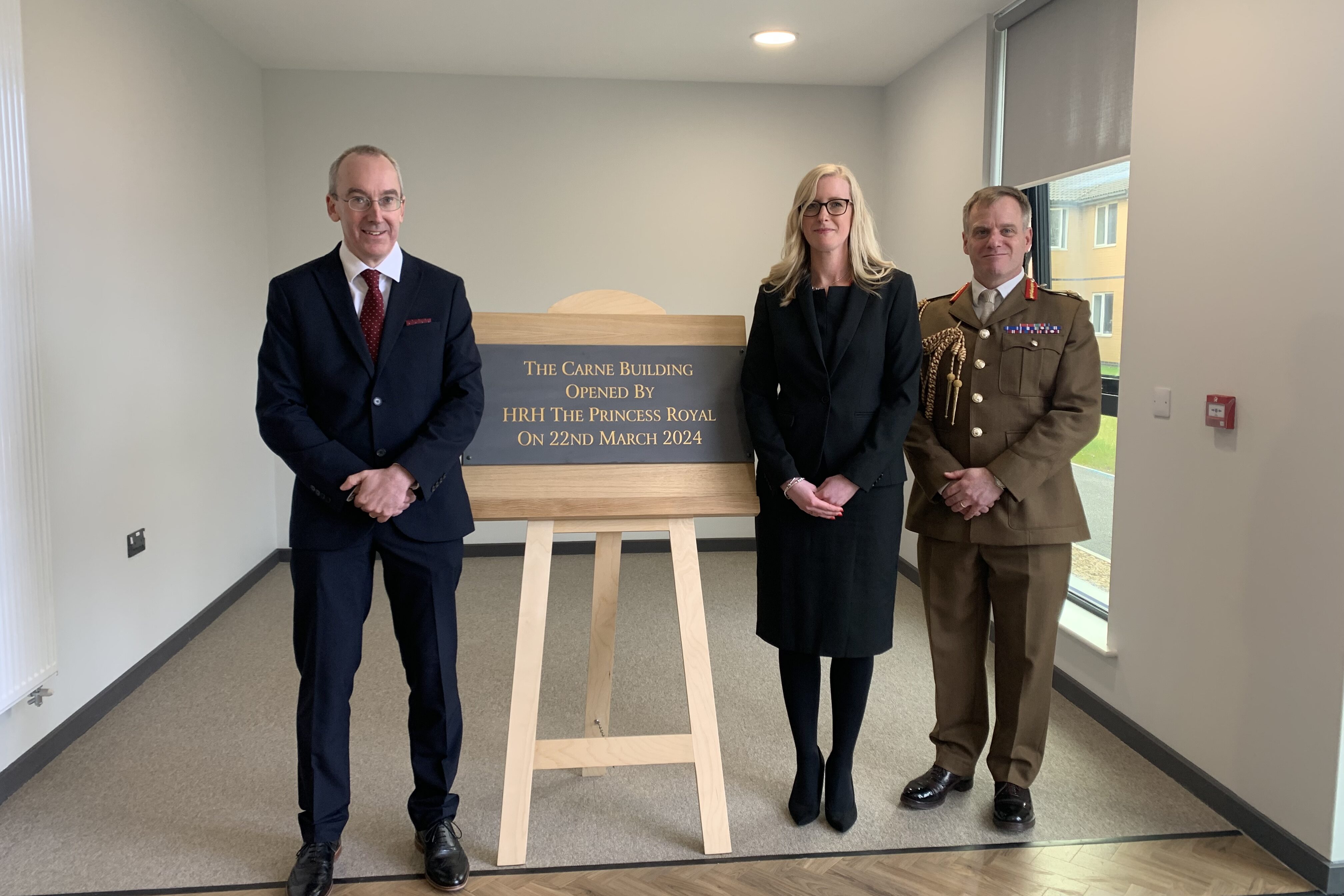 Three people, one in Army uniform, stand by a plaque in a newly opened accommodation block.