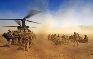 Soldiers boarding a helicopter in dusty conditions in Afghanistan.