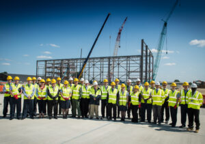 DIO project manager Denis Williams (front centre) with partners celebrating the first stage of A400M hangar’s steelwork at RAF Brize Norton [Crown Copyright/MOD2015]