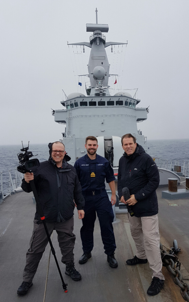 Reservist Ben Lolley on the bow of the Belgian warship BNS Louise Marie with two journalists from Crown Media [Crown Copyright, MOD 2017]