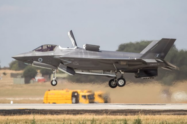 An F-35 landing vertically onto a new landing pad at RAF Marham. The aircraft is a few feet above the ground.