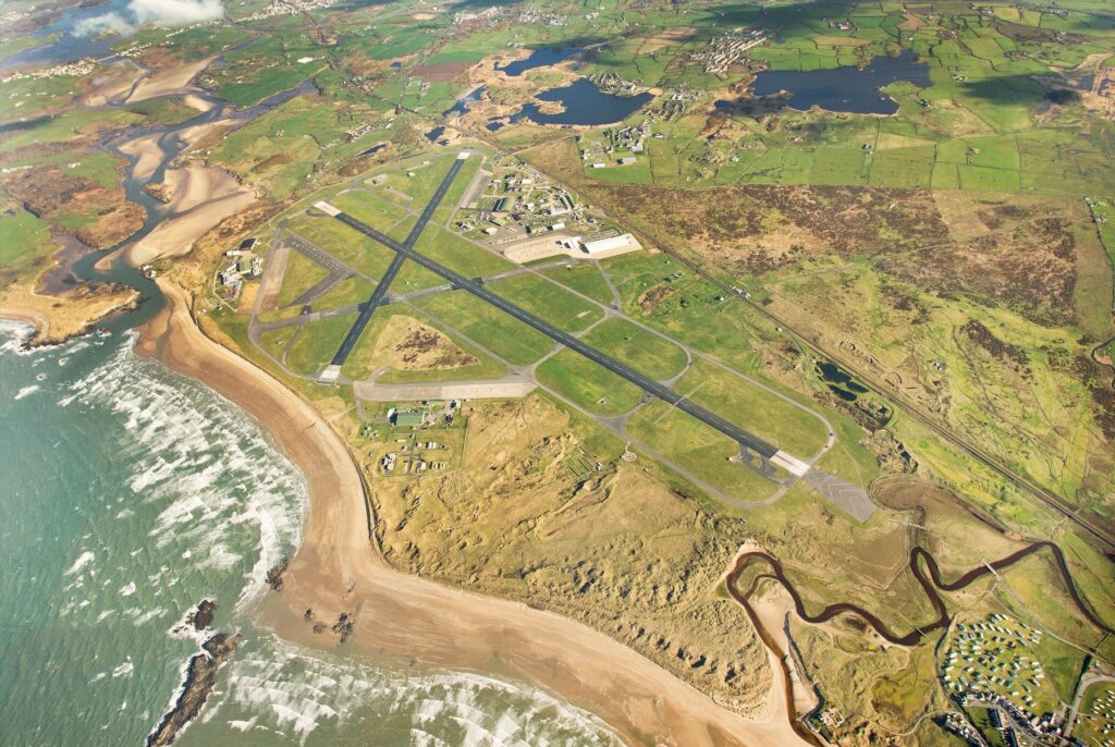 An aerial view of RAF Valley, with the beach and two runways in particular very visible. 