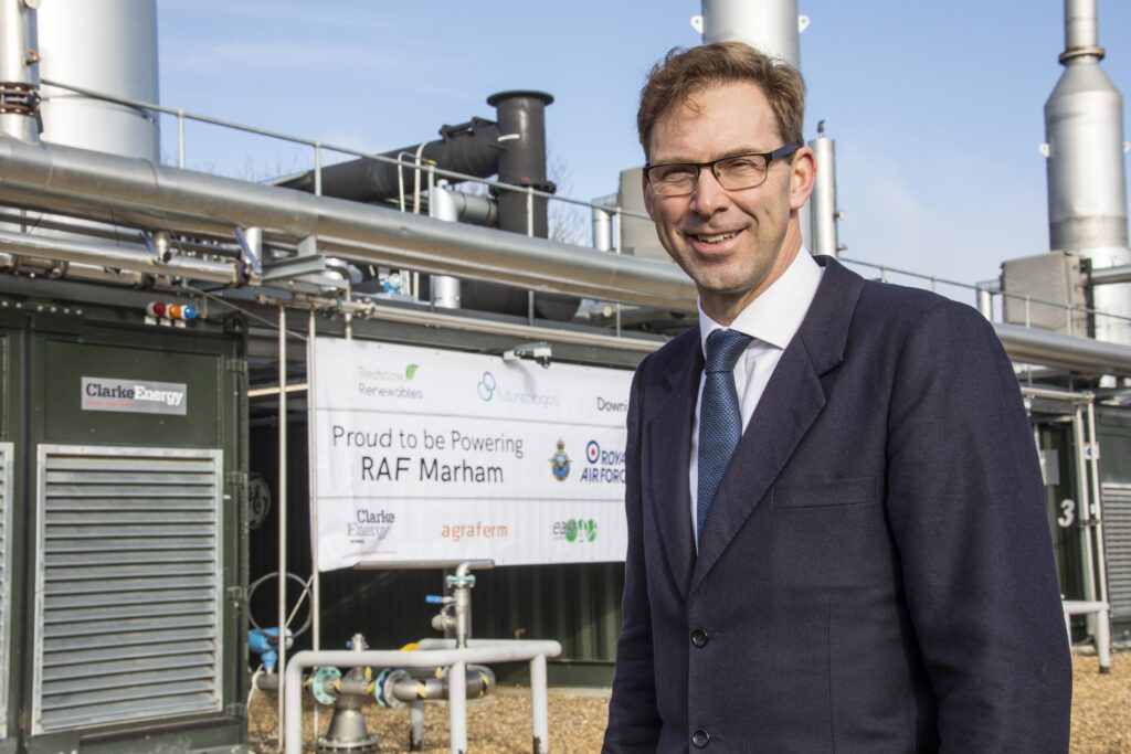 Tobias Ellwood MP standing at the biogas plant, in front of a sign which reads "Proud to be powering RAF Marham".