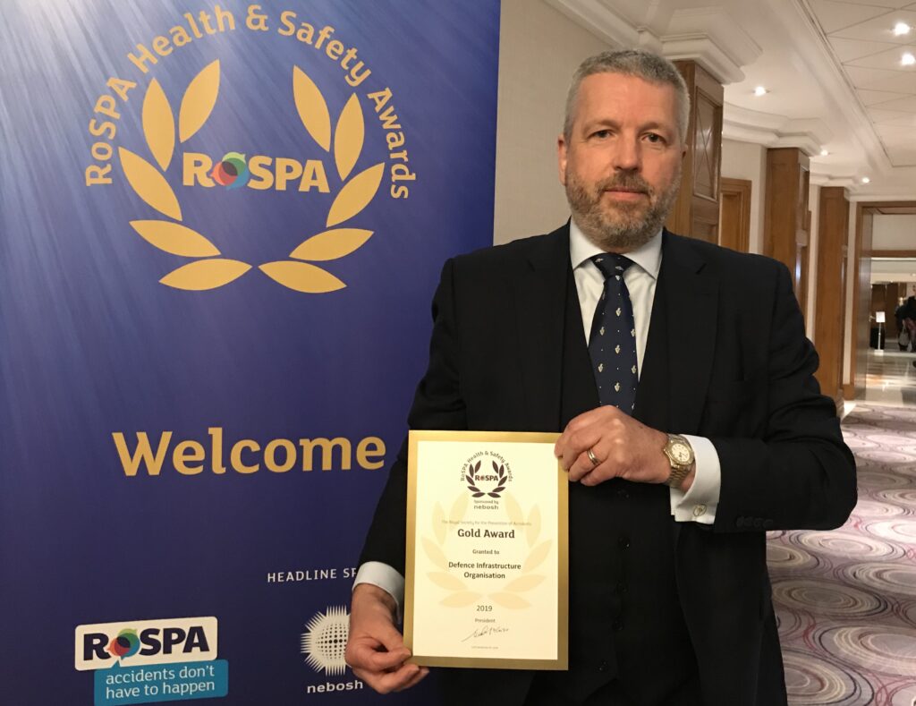 Paul Wilson holding the RoSPA Gold Award certificate in front of a RoSPA banner.