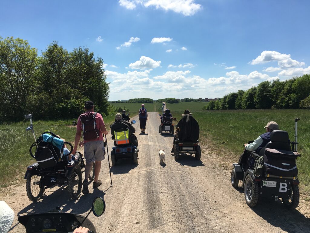 Five members from the Disabled Ramblers on a pathway on the Salisbury Plain Training Area. Around the paths are trees and it is a sunny day.