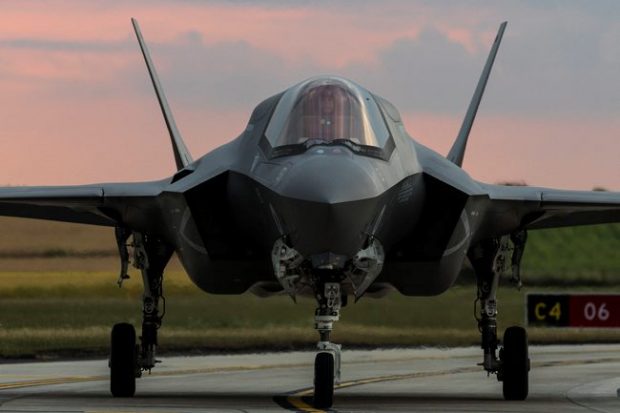 An F-35 jet, facing the camera and on the runway.