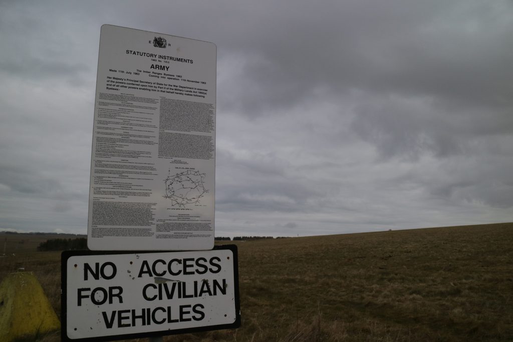 Image of a vertical sign, with densely written text of byelaws. Under that is another sign which says "No access for civilian vehicles" and behind both is a grassy landscape. 