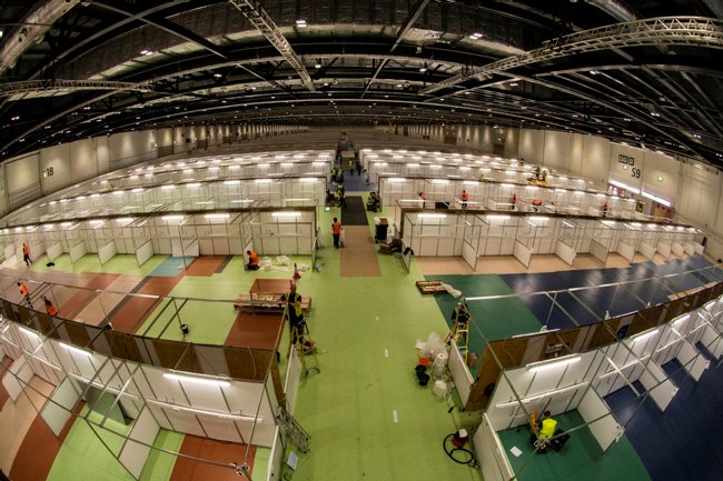 The Nightingale hospital in London under construction. The floor is lime green with sections of white blocks running in columns to accomodate beds. 