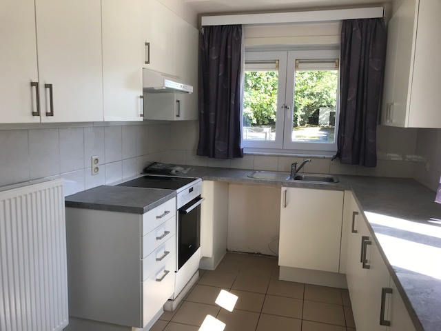 Pictured is a small kitchen with white cabinets and grey surfaces. 