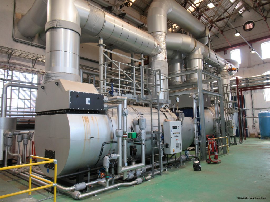 The Combined Heat and Power Plant boiler is silver and has green flooring underneath. 