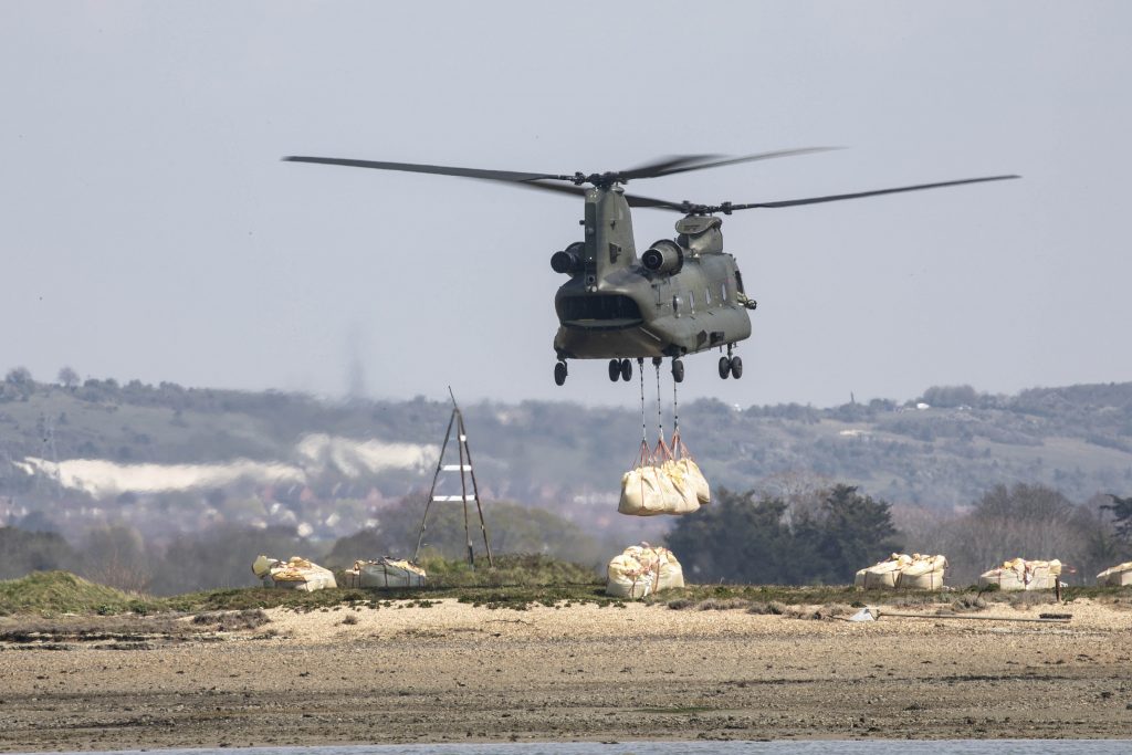 A Chinook lowers large bags of aggregate on to the island.