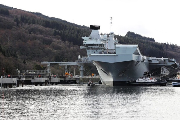 The photo shows HMS Queen Elizabeth, a large aircraft carrier vessel, docked next to the Northern Ammunition Jetty.