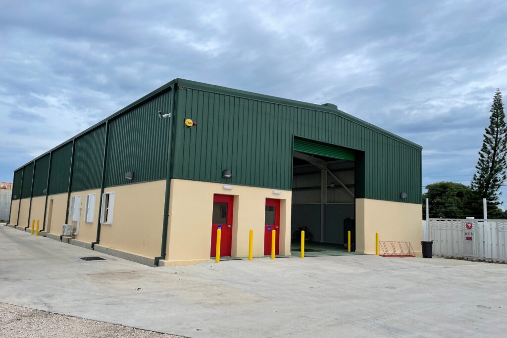 A large warehouse-style building with its lower half painted in a cream colour and its top half painted green.