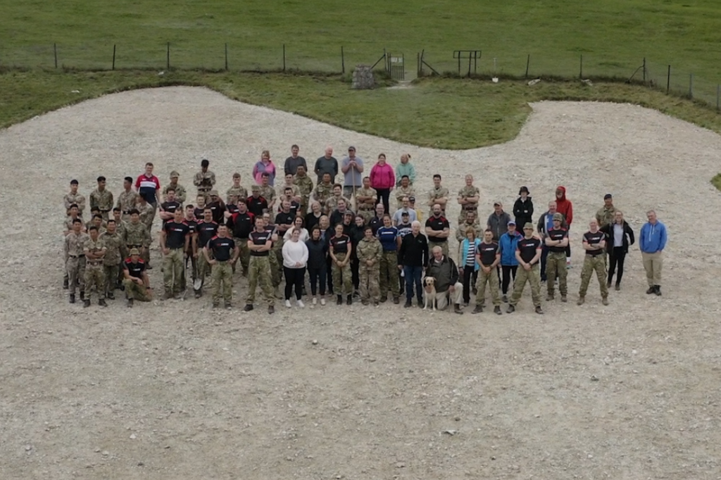 A large group of people standing on a chalk image carved into the side of a hill.