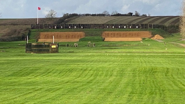 A large grassy area in the foreground and targets in the background.