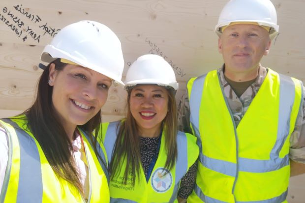 Two women and a man in Army uniform smile at the camera. They are all wearing high-vis jackets and white hard hats.